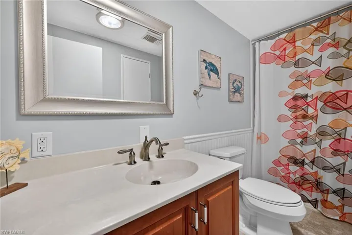 Bathroom featuring a shower with curtain, vanity, and wainscoting