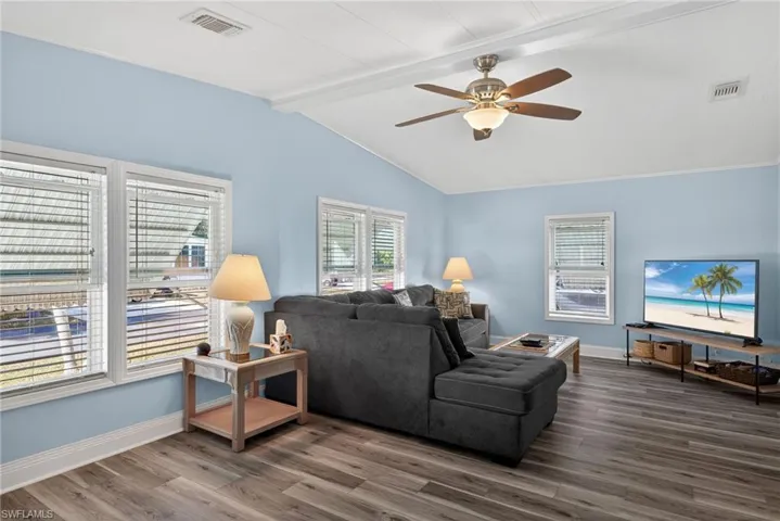 Living area featuring ceiling fan, wood finished floors, and beam ceiling