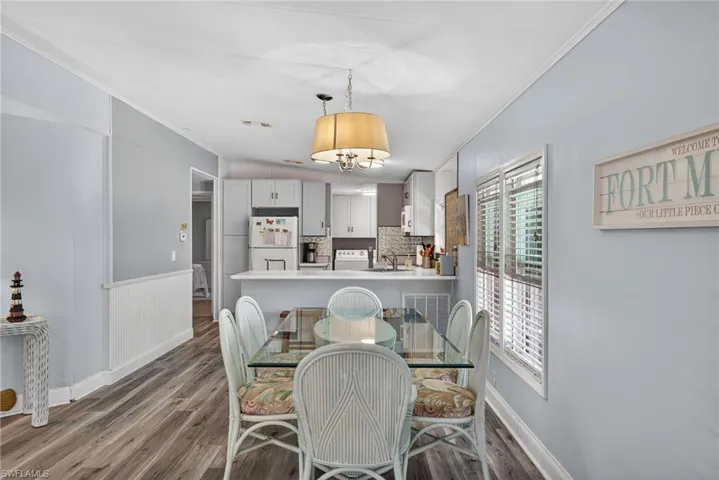 Dining area with ornamental molding, dark wood finished floors, and a wainscoted wall