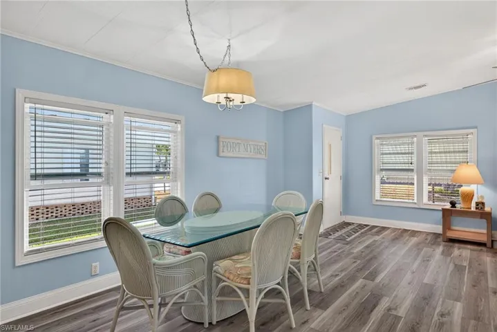 Dining room with wood finished floors, crown molding, and healthy amount of natural light