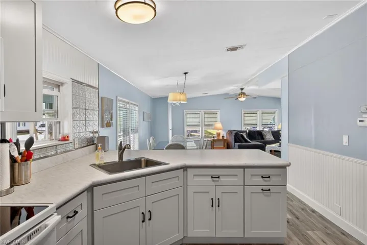 Kitchen featuring a peninsula, crown molding, open floor plan, light wood-type flooring, and light countertops