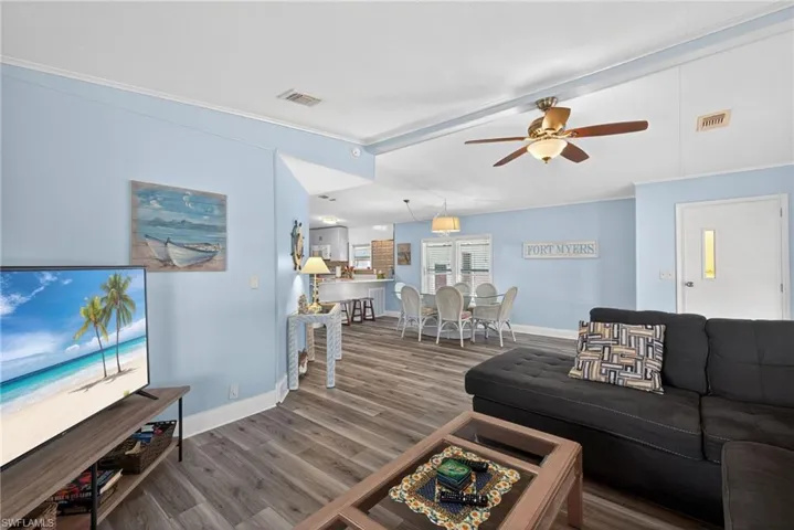 Living room with wood finished floors, crown molding, and a ceiling fan