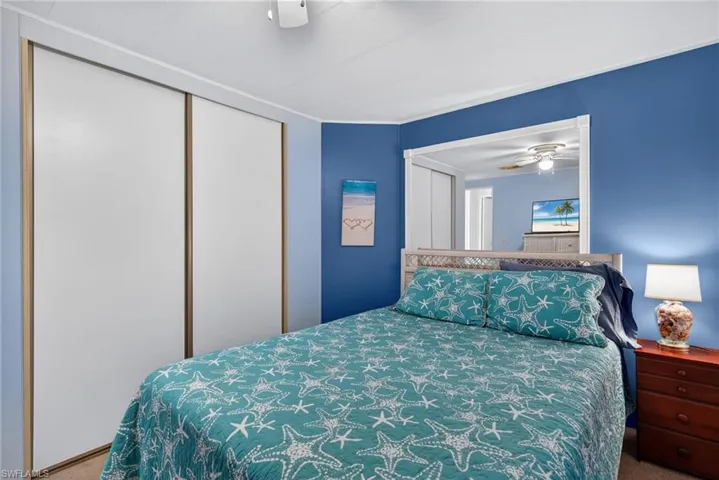 Carpeted bedroom featuring ceiling fan and a closet