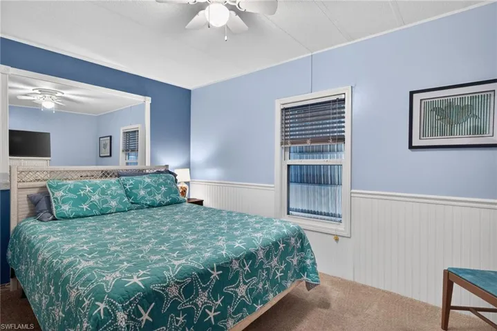 Carpeted bedroom featuring a wainscoted wall and ceiling fan
