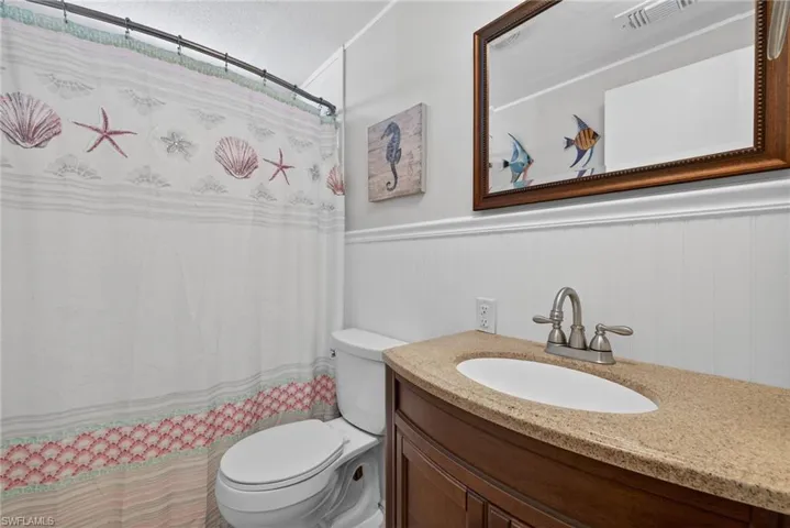 Bathroom featuring a wainscoted wall, vanity, and a shower with curtain