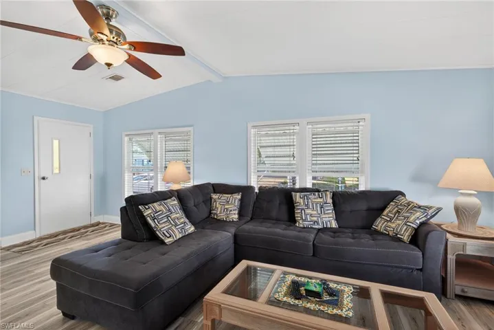 Living area featuring wood finished floors, beam ceiling, and a ceiling fan