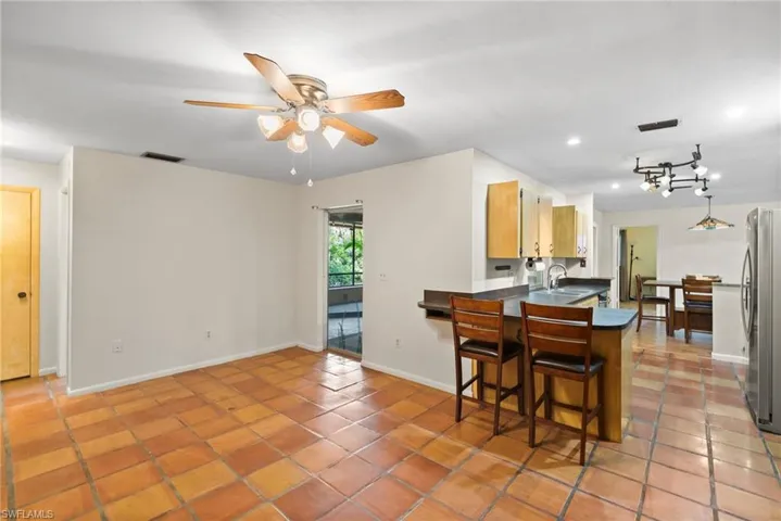Kitchen featuring stainless steel refrigerator, sink, tile patterned floors, a kitchen breakfast bar, and ceiling fan