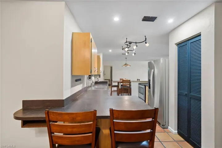 Kitchen with appliances with stainless steel finishes, light tile patterned floors, sink, rail lighting, and kitchen peninsula