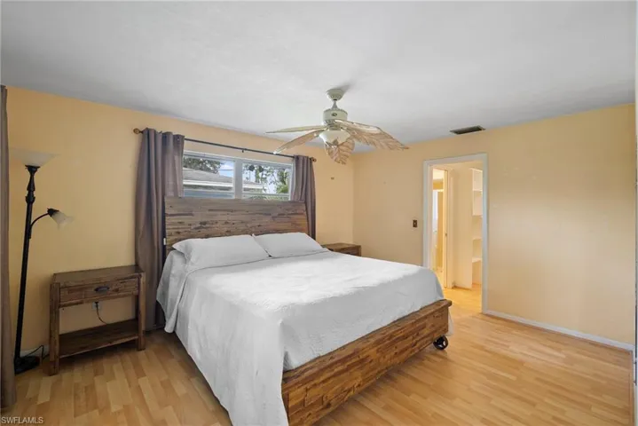 Bedroom with light hardwood / wood-style flooring, ceiling fan, and ensuite bathroom