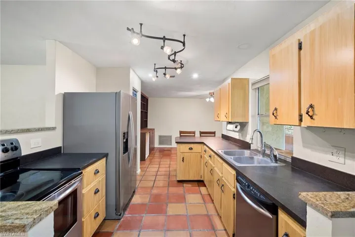 Kitchen with stainless steel appliances, rail lighting, sink, tile patterned floors, and kitchen peninsula