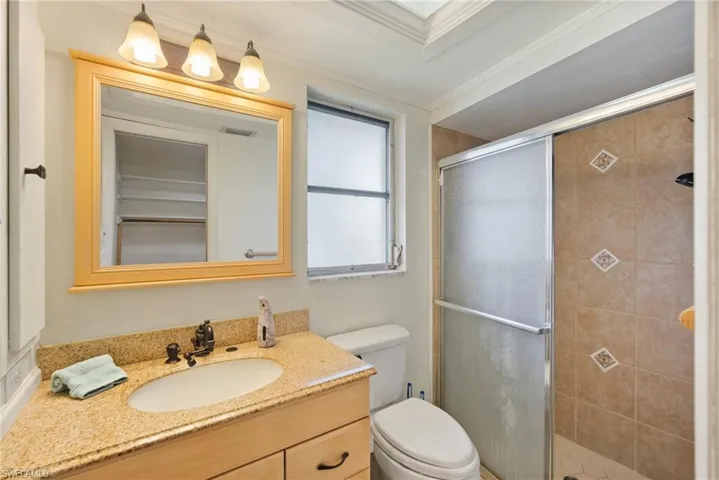 Bathroom with toilet, ornamental molding, an enclosed shower, and vanity