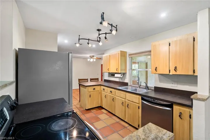 Kitchen with sink, light tile patterned floors, ceiling fan, stainless steel appliances, and kitchen peninsula