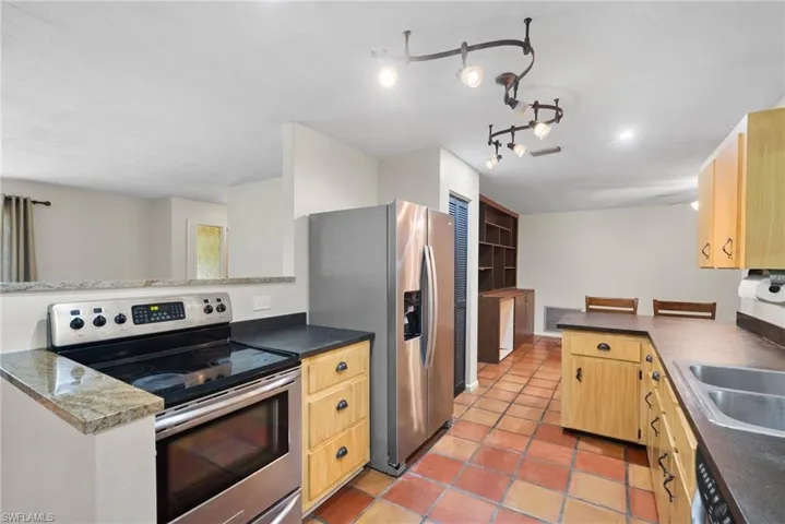 Kitchen featuring kitchen peninsula, track lighting, appliances with stainless steel finishes, and light tile patterned floors