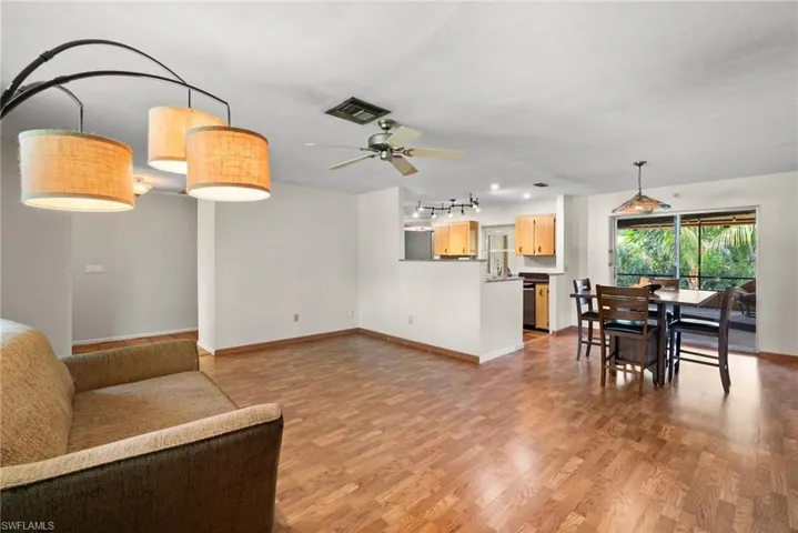 Living room featuring light wood-type flooring, rail lighting, and ceiling fan