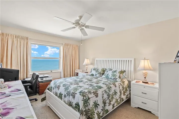Bedroom with light carpet, a desk, and a ceiling fan