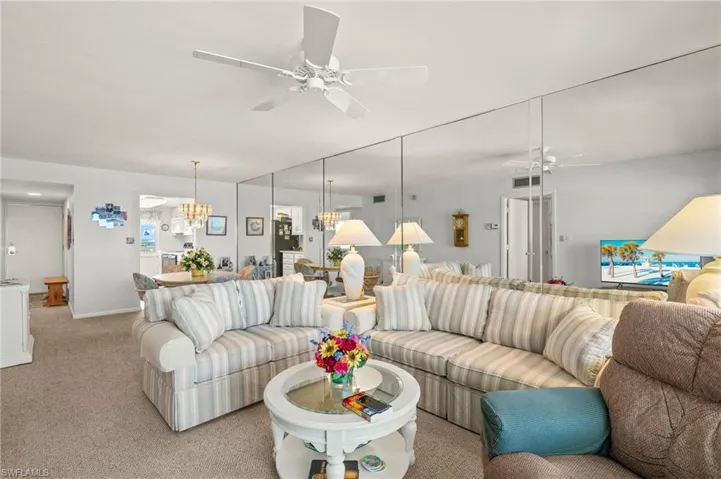 Living area featuring a ceiling fan, light carpet, and a chandelier