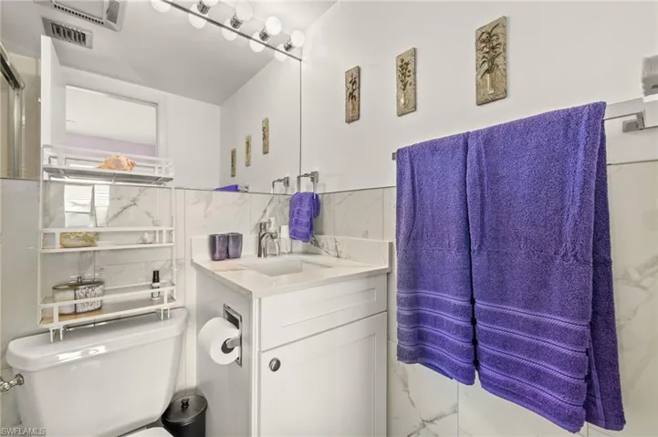 Bathroom featuring vanity and marble look tiles
