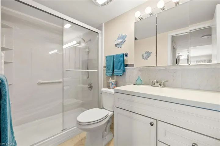 Bathroom with vanity, a stall shower, and decorative backsplash