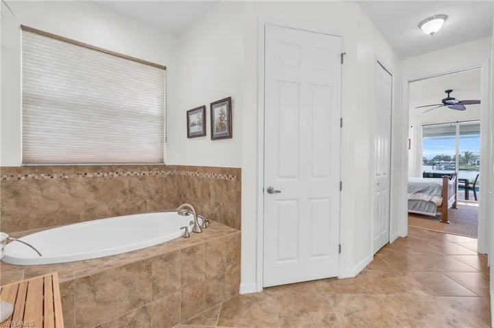 Bathroom featuring a ceiling fan, tile patterned floors, ensuite bath, and a bath