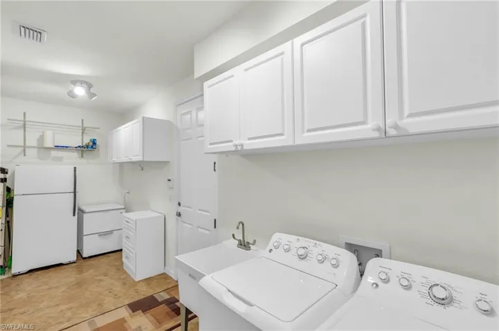 Laundry room with cabinet space, visible vents, washer and dryer, and light floors
