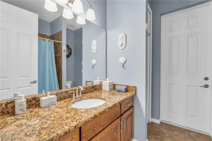 Full bath with tile patterned flooring, vanity, toilet, baseboards, and curtained shower