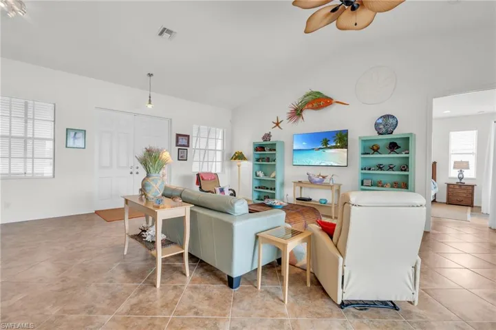 Living room featuring light tile patterned floors, visible vents, and a ceiling fan