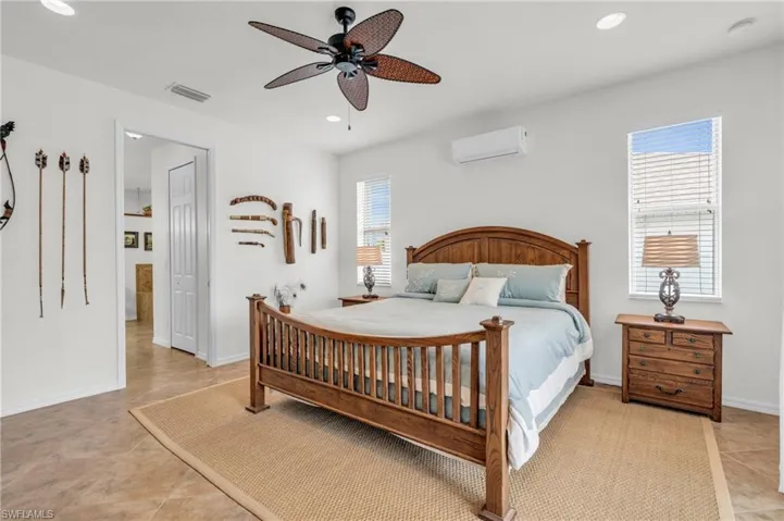 Bedroom featuring recessed lighting, baseboards, a wall mounted air conditioner, and visible vents