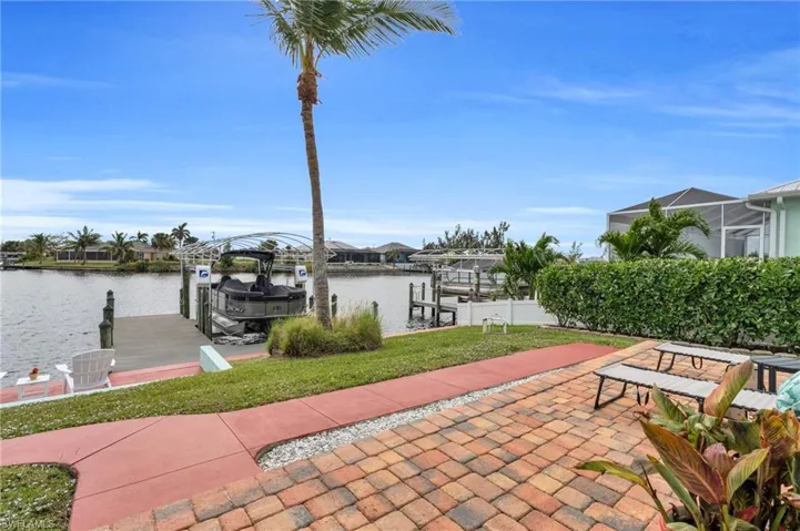 View of dock featuring a water view, boat lift, a patio area, and a yard