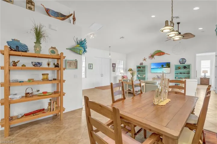 Dining room featuring light tile patterned flooring, vaulted ceiling, ceiling fan, and a healthy amount of sunlight