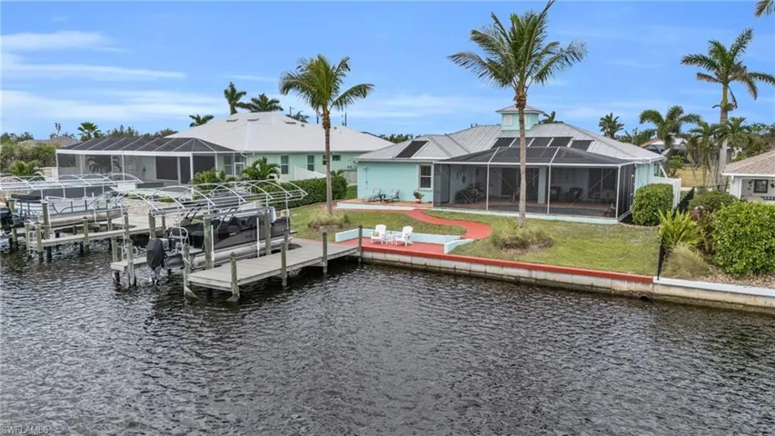 View of dock featuring a lawn, a water view, boat lift, and a lanai
