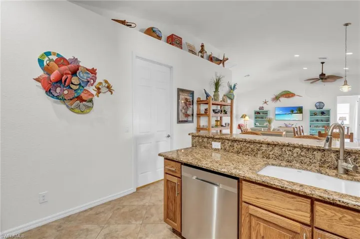 Kitchen featuring a sink, stainless steel dishwasher, open floor plan, light tile patterned floors, and ceiling fan
