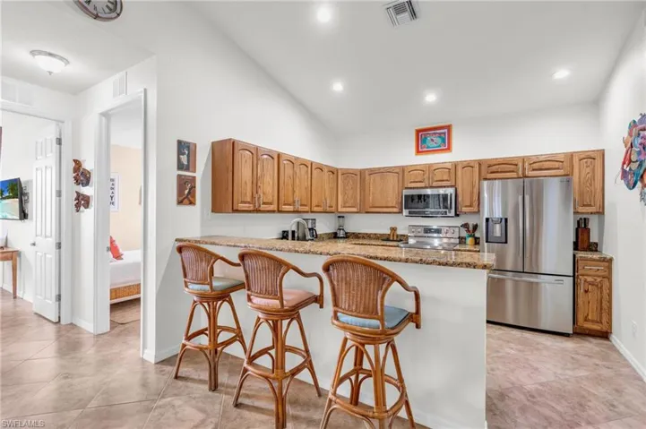 Kitchen with visible vents, brown cabinetry, a kitchen breakfast bar, and appliances with stainless steel finishes