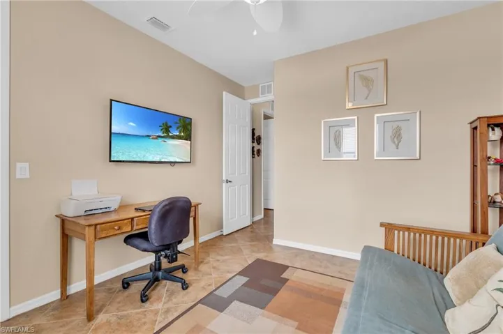 Office area with light tile patterned flooring, baseboards, visible vents, and a ceiling fan