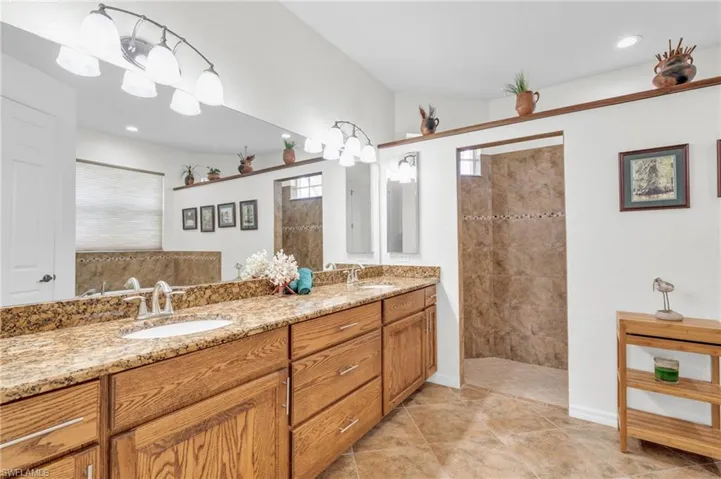 Bathroom with double vanity, baseboards, a sink, and walk in shower