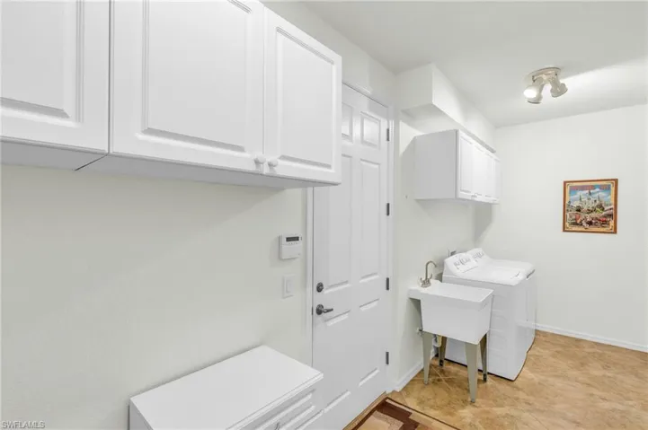 Laundry room featuring independent washer and dryer, cabinet space, baseboards, and a sink
