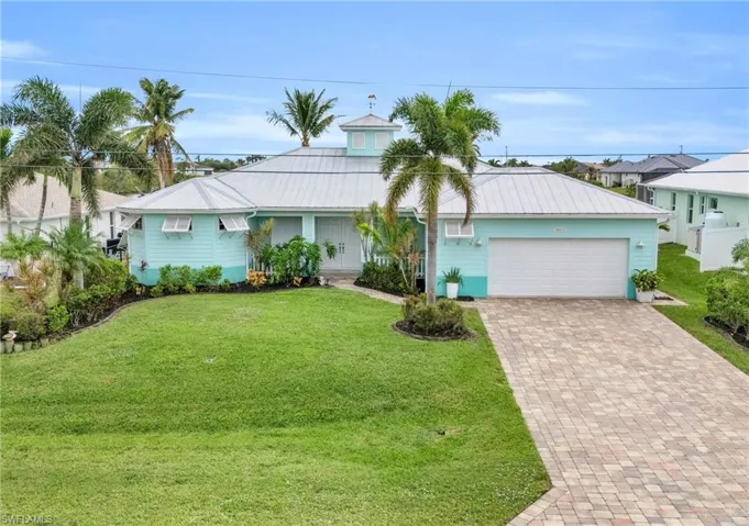 View of front of house featuring a front yard, decorative driveway, a garage, and metal roof