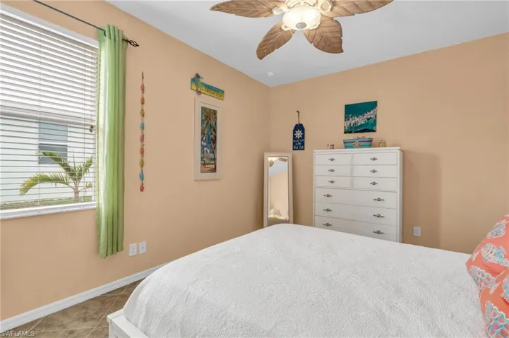 Bedroom featuring baseboards, a ceiling fan, and light tile patterned floors