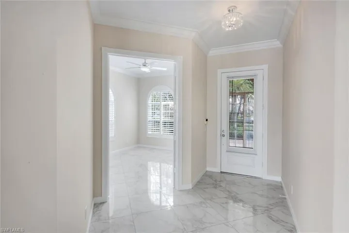 Entryway with ornamental molding, light marble finish flooring, a chandelier, and ceiling fan
