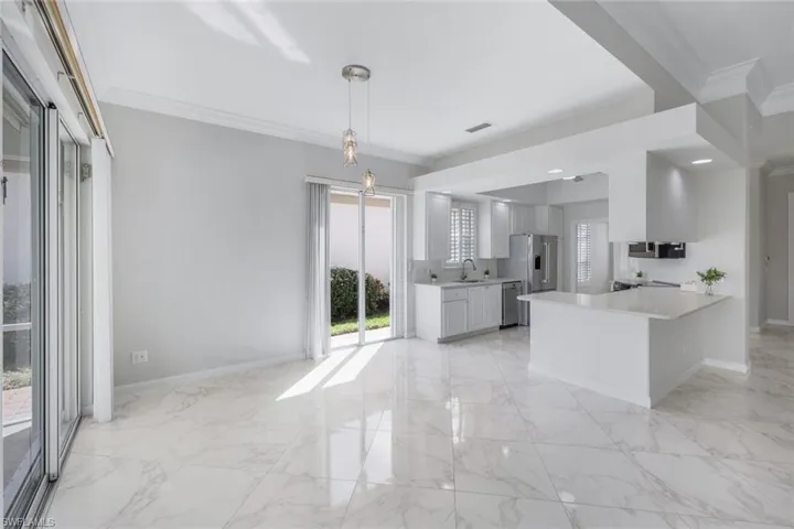 Kitchen featuring ornamental molding, light marble finish flooring, white cabinets, a peninsula, and decorative backsplash