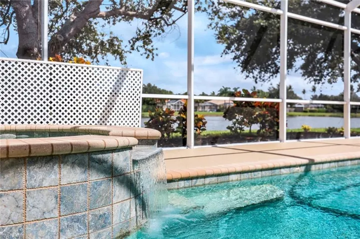 Outdoor pool featuring glass enclosure, a sunroom, and a water view
