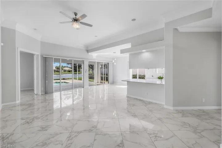 Unfurnished room featuring ornamental molding, light marble finish floors, and ceiling fan