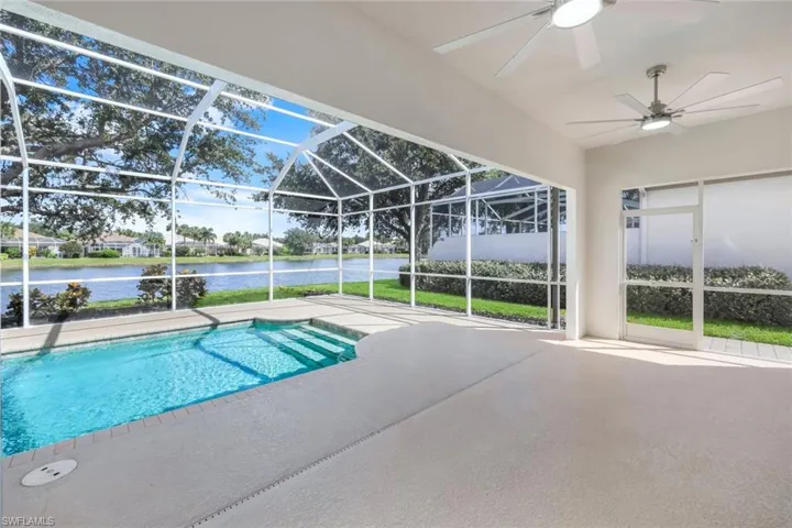 Outdoor pool featuring glass enclosure, a patio area, a water view, and a sunroom