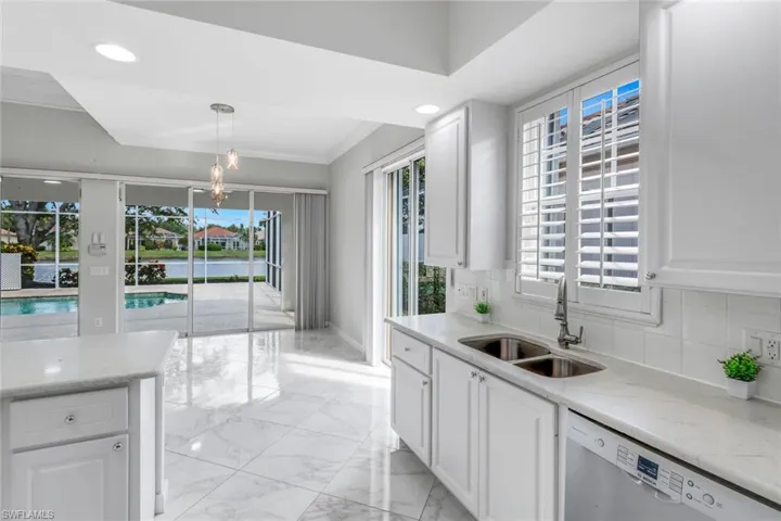 Kitchen featuring dishwasher, white cabinets, a chandelier, light marble finish floors, and recessed lighting