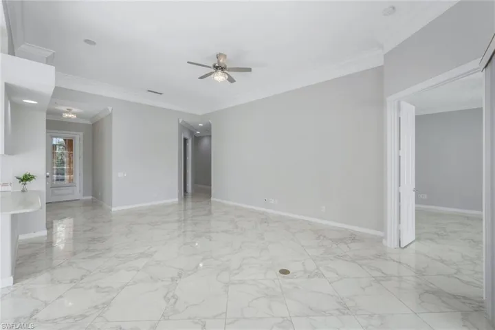 Unfurnished room with ornamental molding, light marble finish flooring, and a ceiling fan