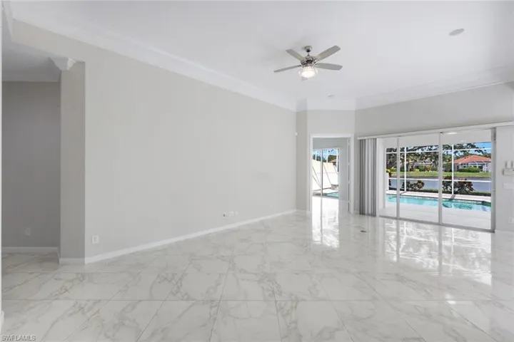 Spare room with light marble finish flooring, ornamental molding, and ceiling fan