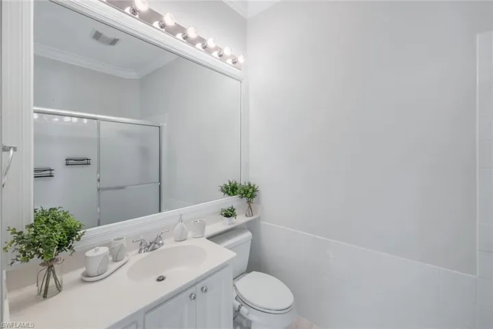 Bathroom with vanity, ornamental molding, a stall shower, tile walls, and wainscoting