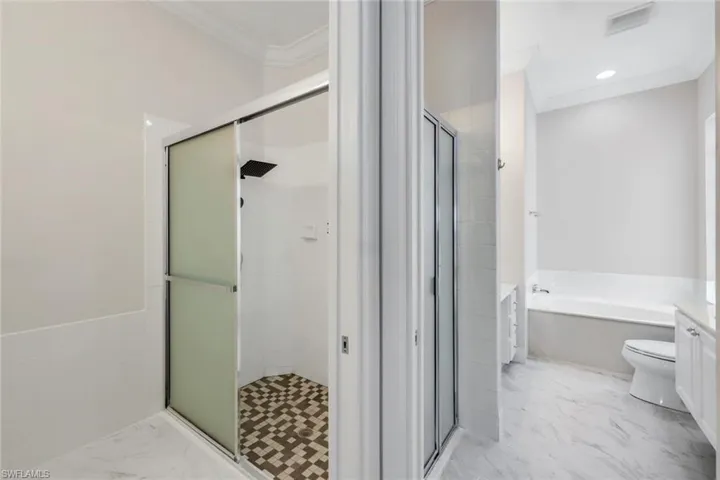 Bathroom with vanity, ornamental molding, a stall shower, a garden tub, and light marble finish floors