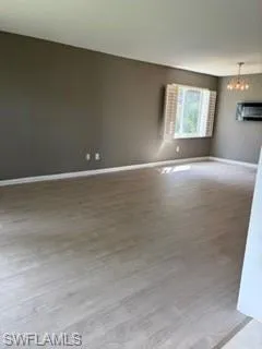 Empty room with light wood finished floors and suspended lighting