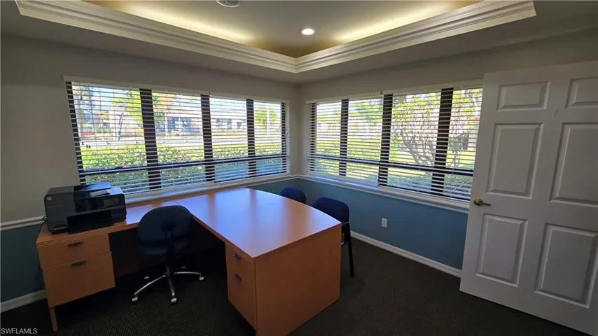 Office featuring dark colored carpet, plenty of natural light, a raised ceiling, and crown molding