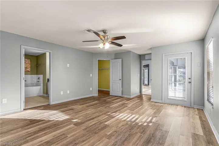Unfurnished bedroom featuring a walk in closet, ceiling fan and adjoining bathroom